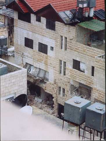 The bulldozer has knocked out the second story windows and torn down the ground floor wall.