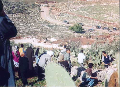 Soldiers and border police start to deploy as villagers make their way down into the valley where the bulldozers are.
